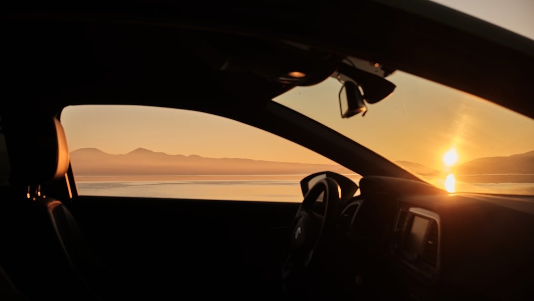 The sun is setting in the distance behind a car