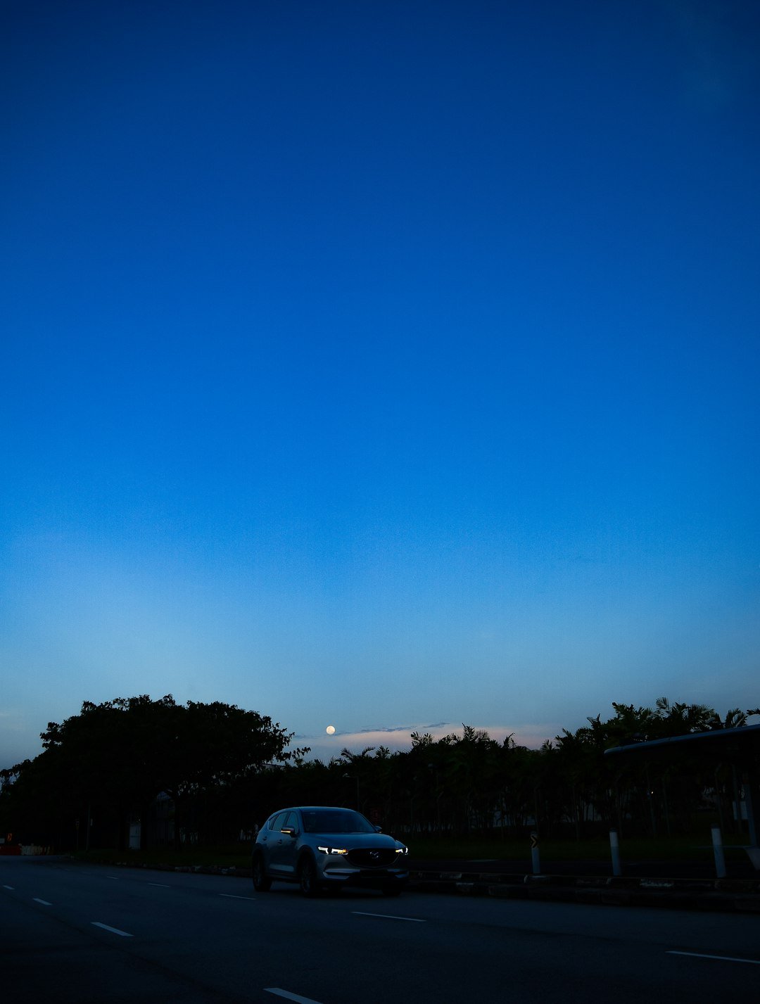 a car driving down a street under a blue sky