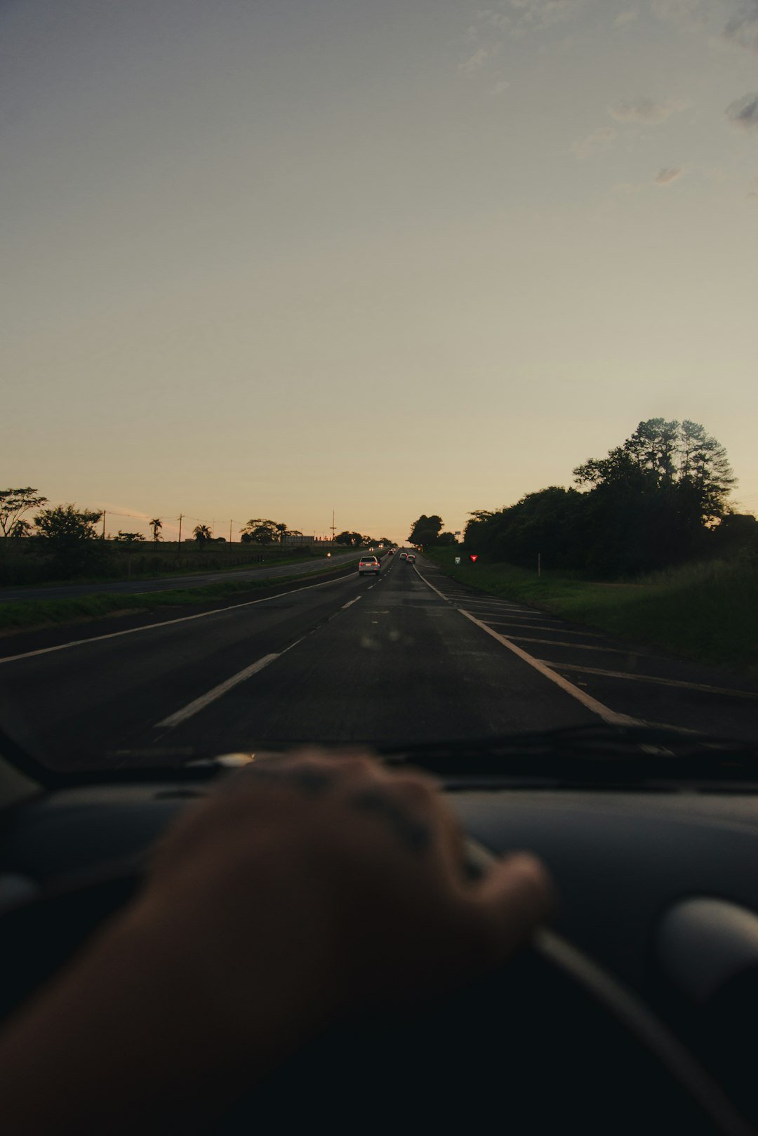 a person driving a car down a road at sunset