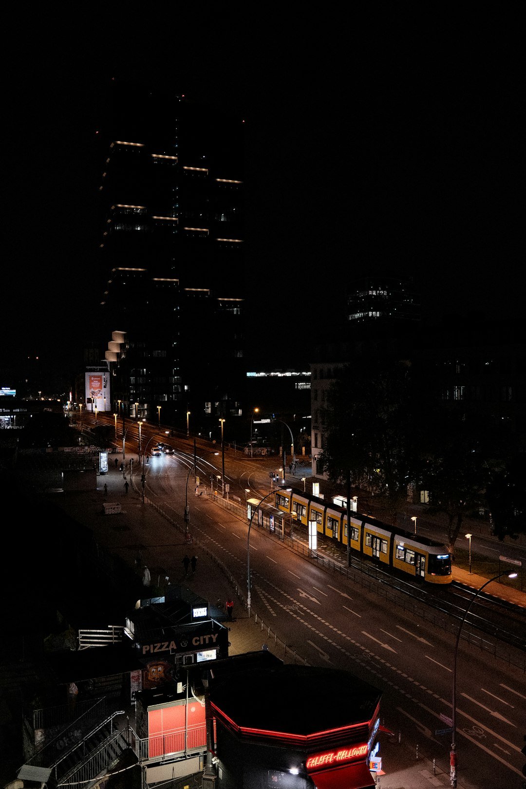 a city street at night with a train on the tracks