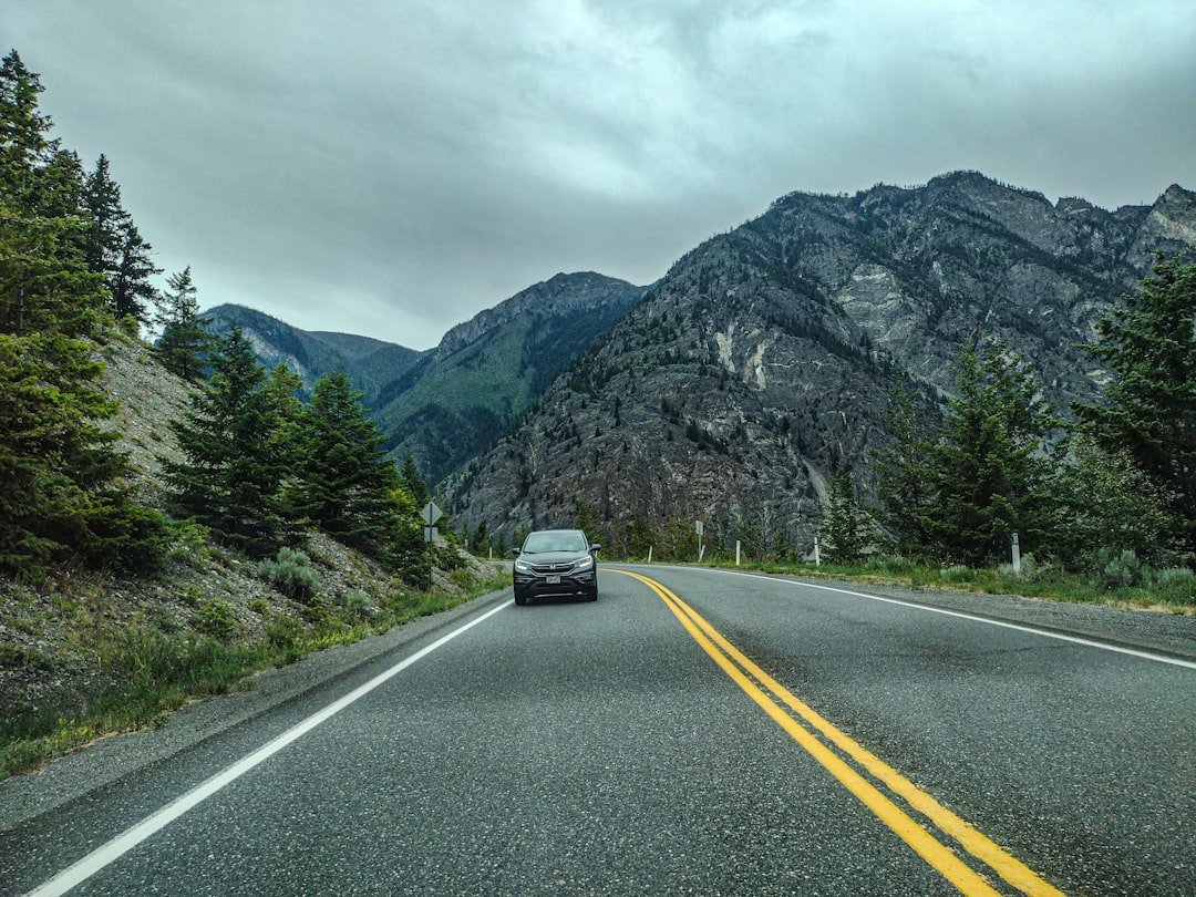 A car driving down a road with mountains in the background